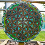 Mandala végétal réalisé avec des pétales en céramique, du verre, et des pierres de laplage, dan les couleurs verts.